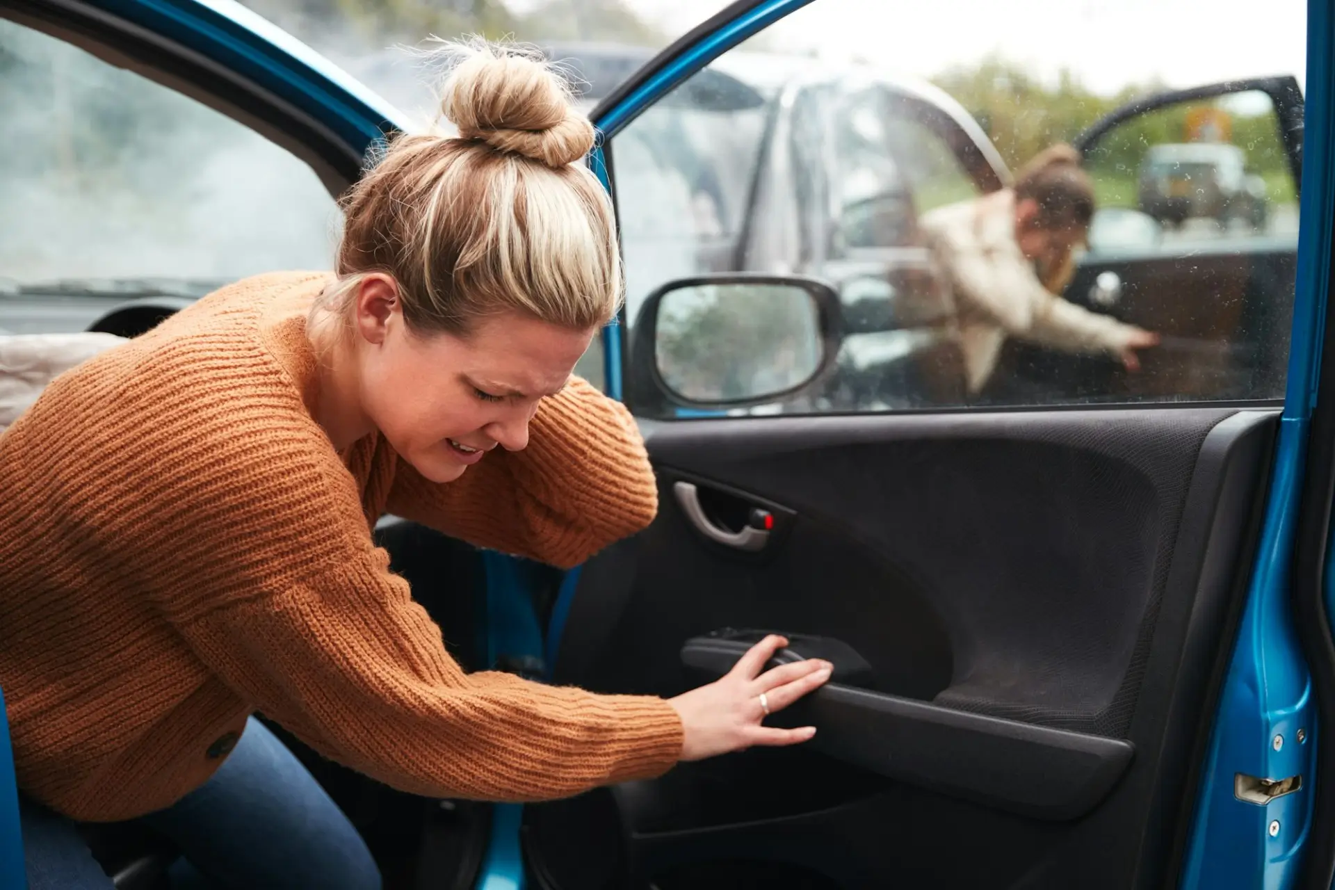 Woman experiencing pain after a collision while exiting her vehicle, illustrating the need for early evaluation, car accident treatment, and auto injury rehab at Canyon Lake Chiropractic and Physical Therapy.