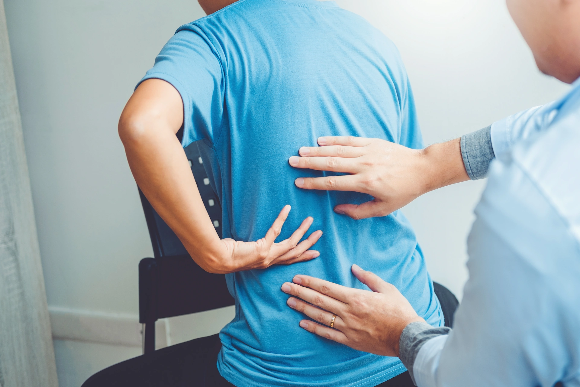 Provider assessing low back pain during an exam to determine whether spinal decompression therapy or a chiropractic adjustment is the best treatment option.